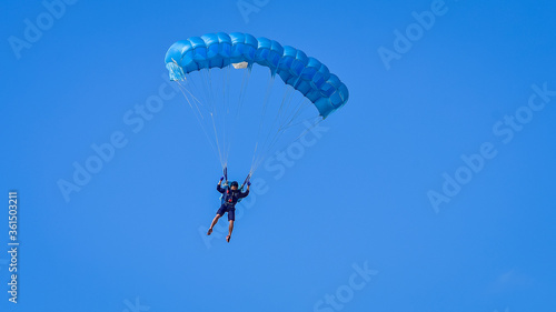 Skydiver and colorful parachute on the blue sky 