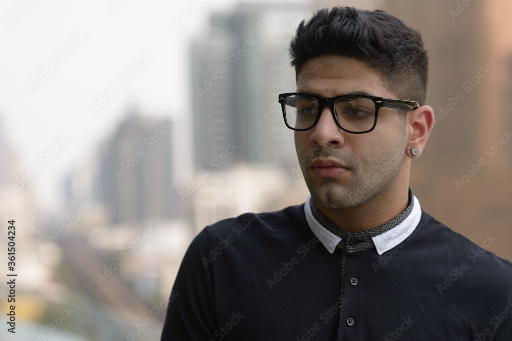 Face of stressed young Indian man with eyeglasses thinking in the city Face of stressed young Indian man with eyeglasses thinking in the city