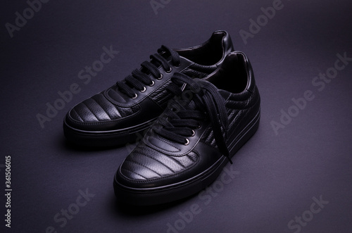 Fashionable genuine leather sneakers on a black background. Fashionable footwear.