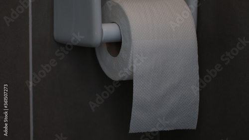 Toilet paper, white circular roll in the four, put beside the wall in the bathroom. The picture has some clarity.