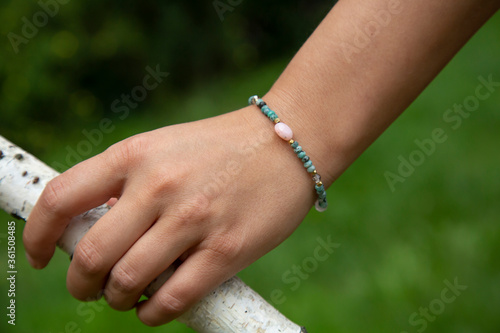 Outdoor detail of female hand wearing mineral crystals round beads bracelet © marbenzu