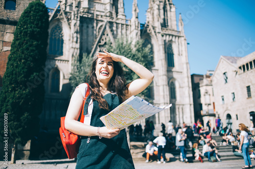 Obraz na płótnie Cheerful caucasian female traveler in casual wear hiding his face from sunny on