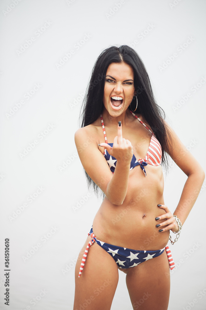 Naklejka premium A woman in a swimsuit with an American flag walks along the coast