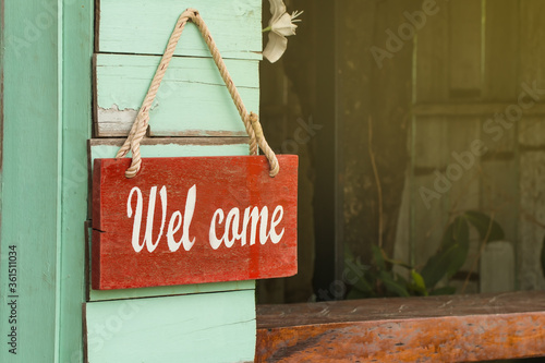 Welcome message label, white characters On a red background Hang it with a rope Beside the greenwood wall