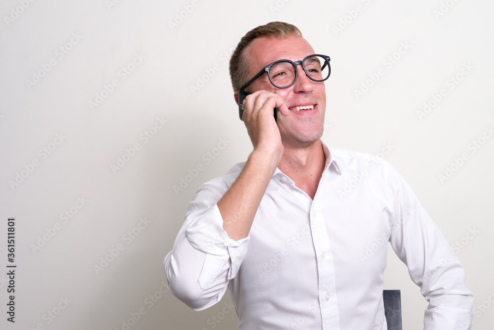 Happy businessman with blond hair wearing eyeglasses and talking on the phone