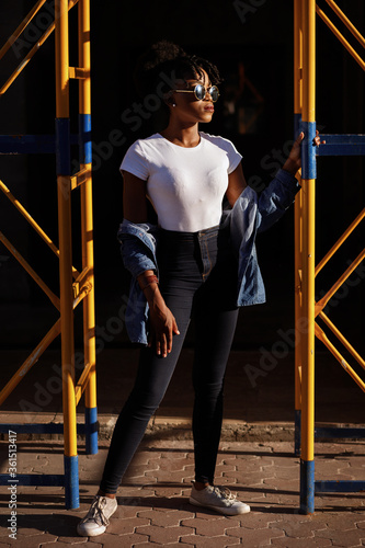 Stylish dark-skinned girl in town. Street style. African girl with glasses. Hipster