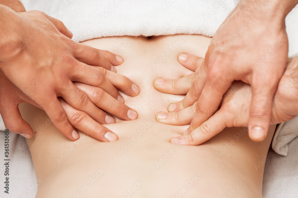 Woman receiving back massage with four hands of two male therapists close up. Woman receiving back massage with four hands of two male therapists close up.