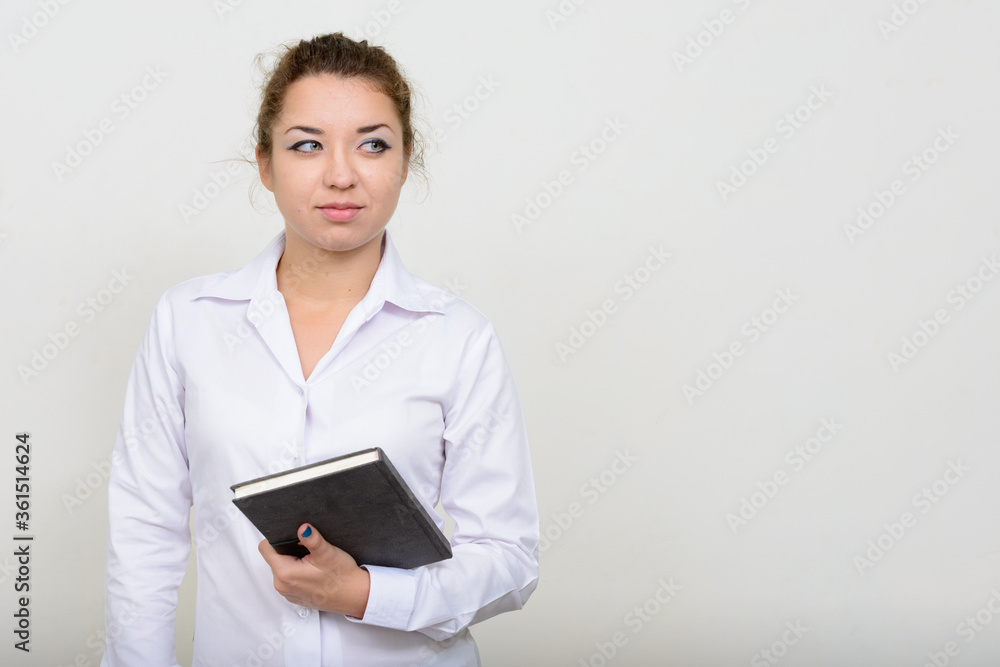 Portrait of young beautiful businesswoman thinking while holding book Portrait of young beautiful businesswoman thinking while holding book