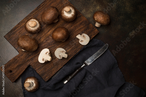 Fresh champignon mushrooms on a cutting board and on a black background