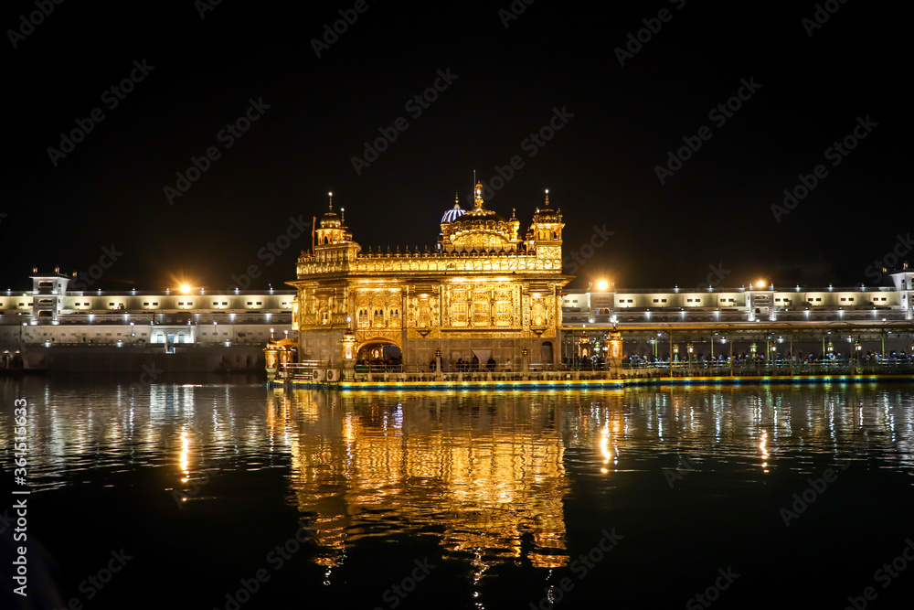 golden temple with reflection in the water at night