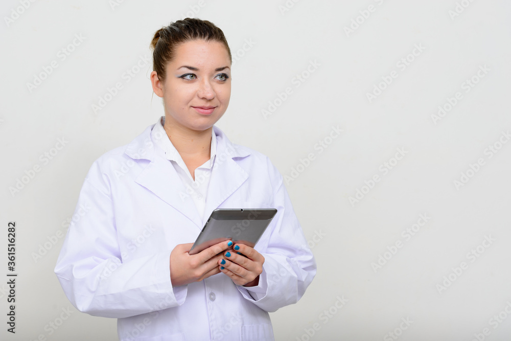 Portrait of young beautiful woman doctor thinking while using digital tablet Portrait of young beautiful woman doctor thinking while using digital tablet