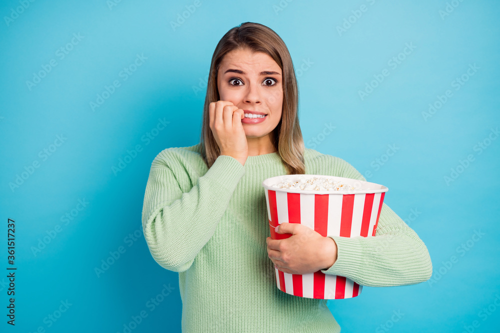 Close-up portrait of her she nice-looking attractive lovely worried scared girl eating corn watching scary tv show biting nails isolated over bright vivid shine vibrant blue color background