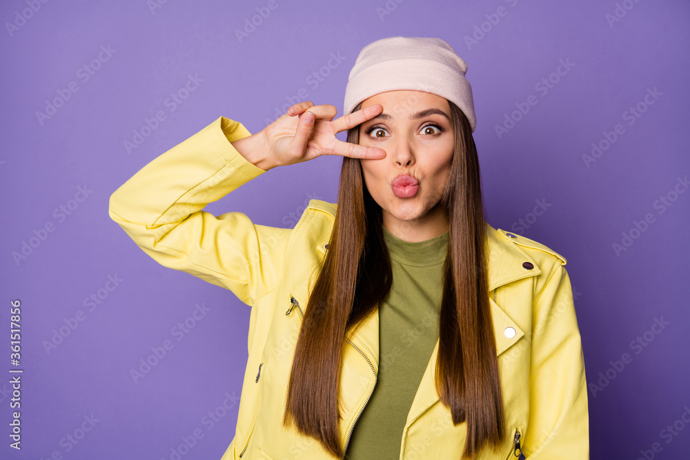 Photo of pretty nice lady good mood showing v-sign symbol near eye sending air kisses wear bright yellow leather jacket green shirt modern cap isolated pastel purple color background Photo of pretty nice lady good mood showing v-sign symbol near eye sending air kisses wear bright yellow leather jacket green shirt modern cap isolated pastel purple color background