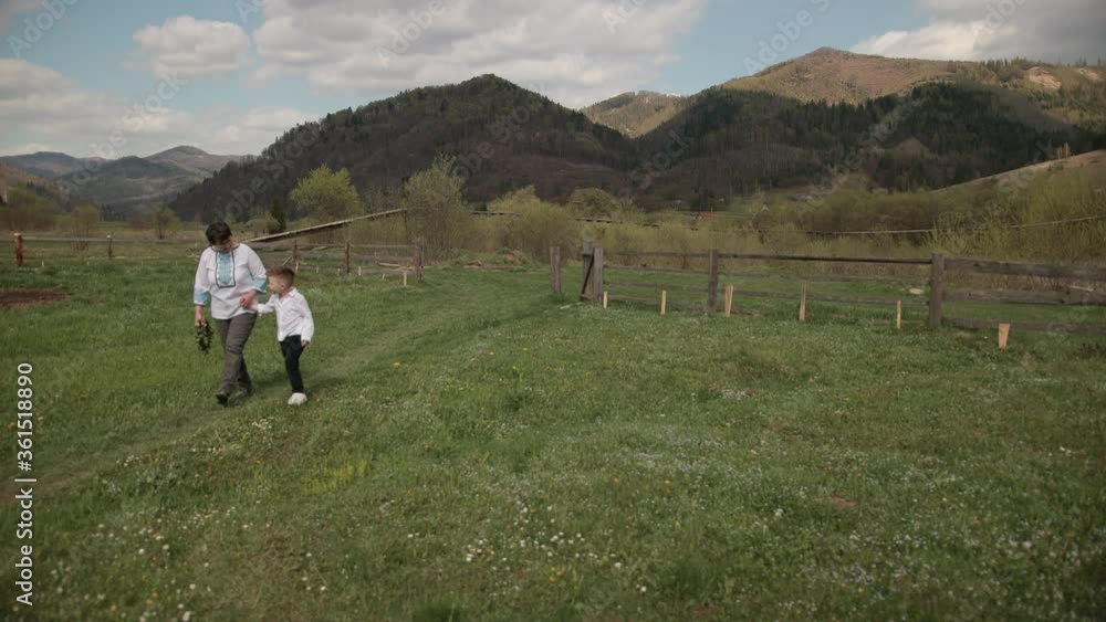Grandchild supports grandma when walking, a grandson goes through nature with his grandparent, listening to their stories, outdoor over mountain on background, generarion family. Bright sunny day Grandchild supports grandma when walking, a grandson goes through nature with his grandparent, listening to their stories, outdoor over mountain on background, generarion family. Bright sunny day