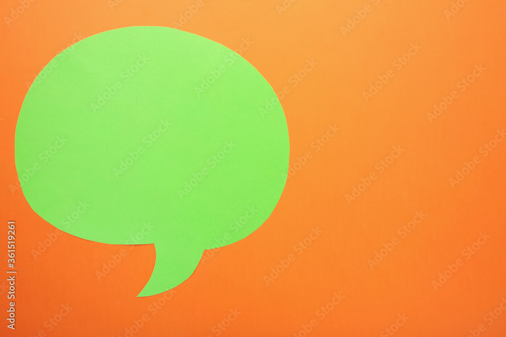 Green paper speech bubble on orange background Green paper speech bubble on orange background