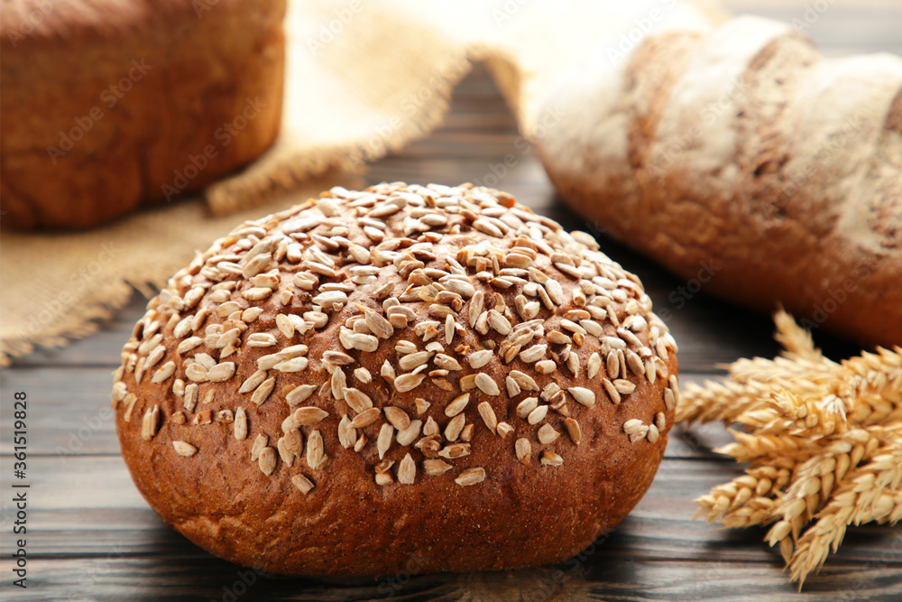 Fresh dark bread with spikelet of wheat on brown wooden table