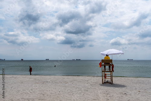 lifeguard tower on the beach. lifeguard sitting on surveillance tower, front of the sea. Lifeguard Beach Chair. Beach lifeguard on duty. Cloudy sky.  photo