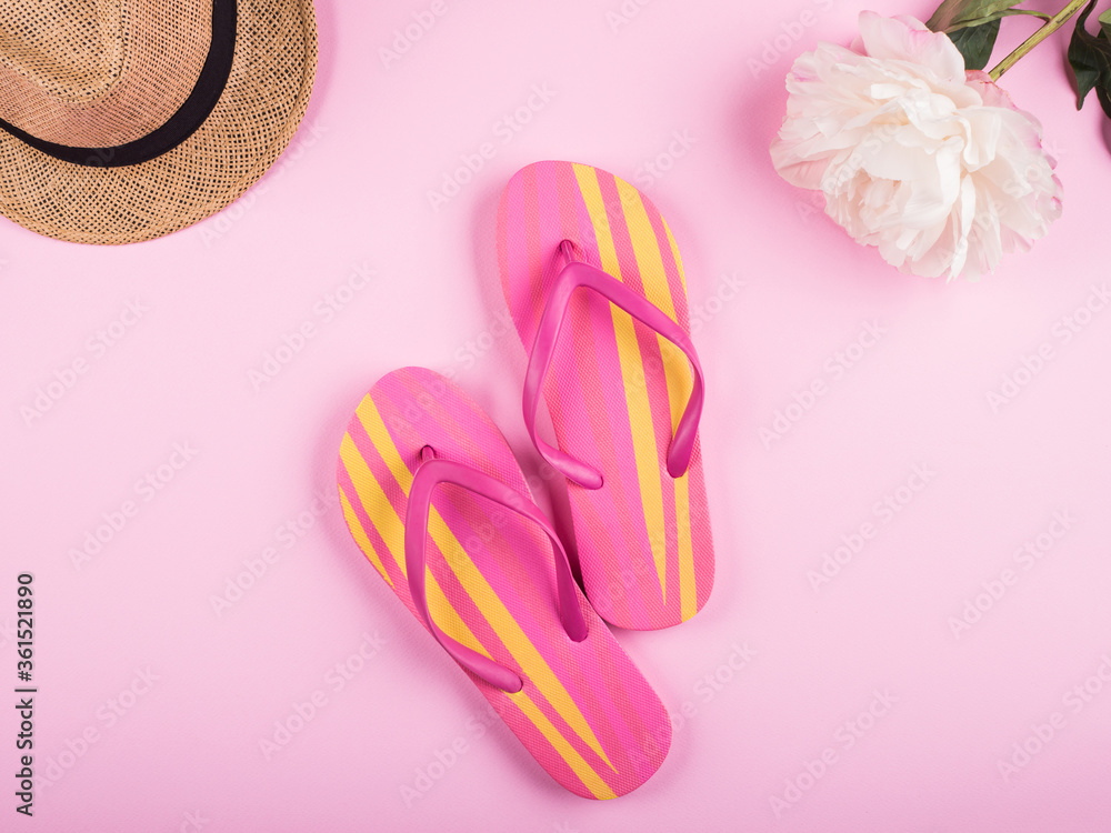 Pink and yellow female flip flops. Flat lay on pink background with peonies. Hello summer vacation