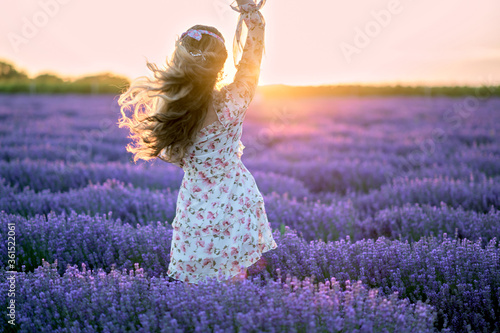 Fototapeta Naklejka Na Ścianę i Meble -  Happy woman dancing in a lavender field at sunset. Beautiful flowers meadow. Summer sunset colorful lighting