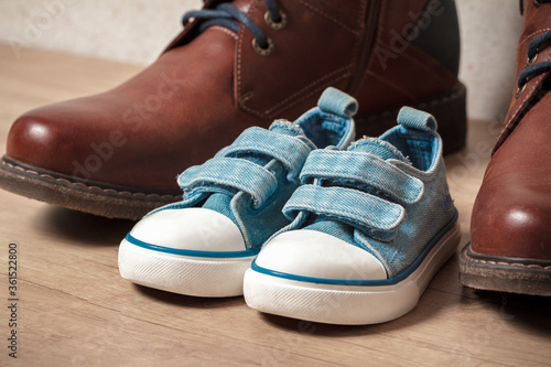 Men's and children's shoes on a wooden floor