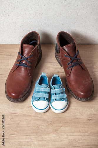 Men's and children's shoes on a wooden floor