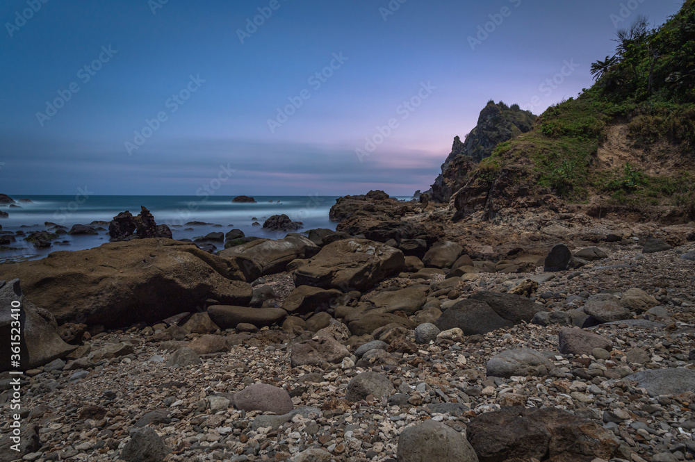 Long exposure shot of rock beach with soft motion blue sky background Long exposure shot of rock beach with soft motion blue sky background