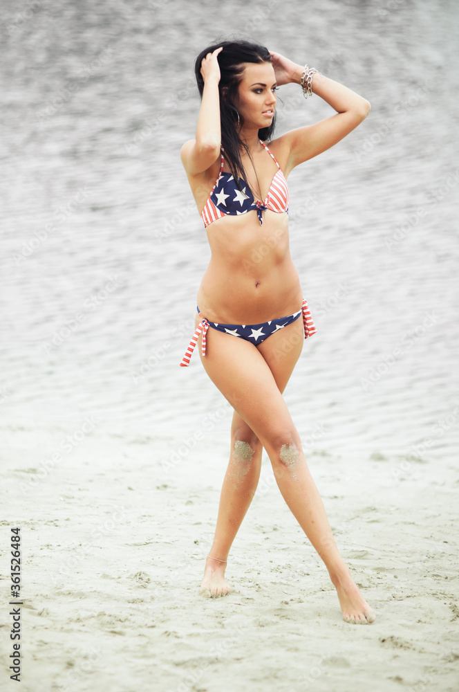 Obraz premium Woman on the beach in a bathing suit with an American flag having fun