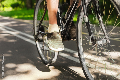 Man foot in sport shoes on the pedal of mountain bike on outdoor trail in park. Active summer solo outdoor activity. Close up. Man cycling in nature. Training, sport activity and health care.