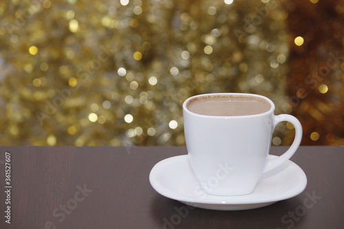 White cup of coffee with milk, lights glittering bokeh. Celebrate, Christmas, New Year, holiday party background.