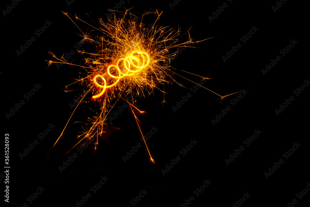 A spiral of light from a sparkling burning sparkler or salute on a black background. Holiday concept, copy space