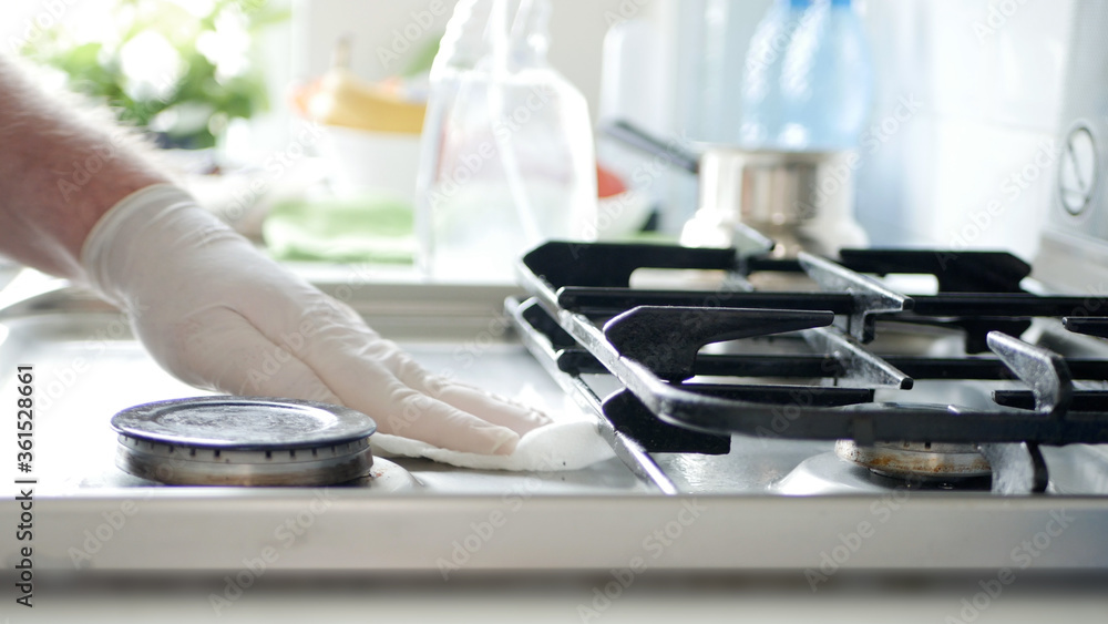 Busy Person in the Kitchen Wearing Gloves Cleans with Solution the Cooker Stove. Busy Person in the Kitchen Wearing Gloves Cleans with Solution the Cooker Stove.