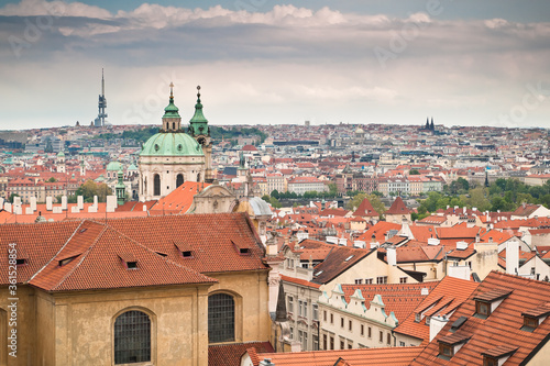 View of red roofs of Prague along with St. Nicholas church and Zizkov tower
