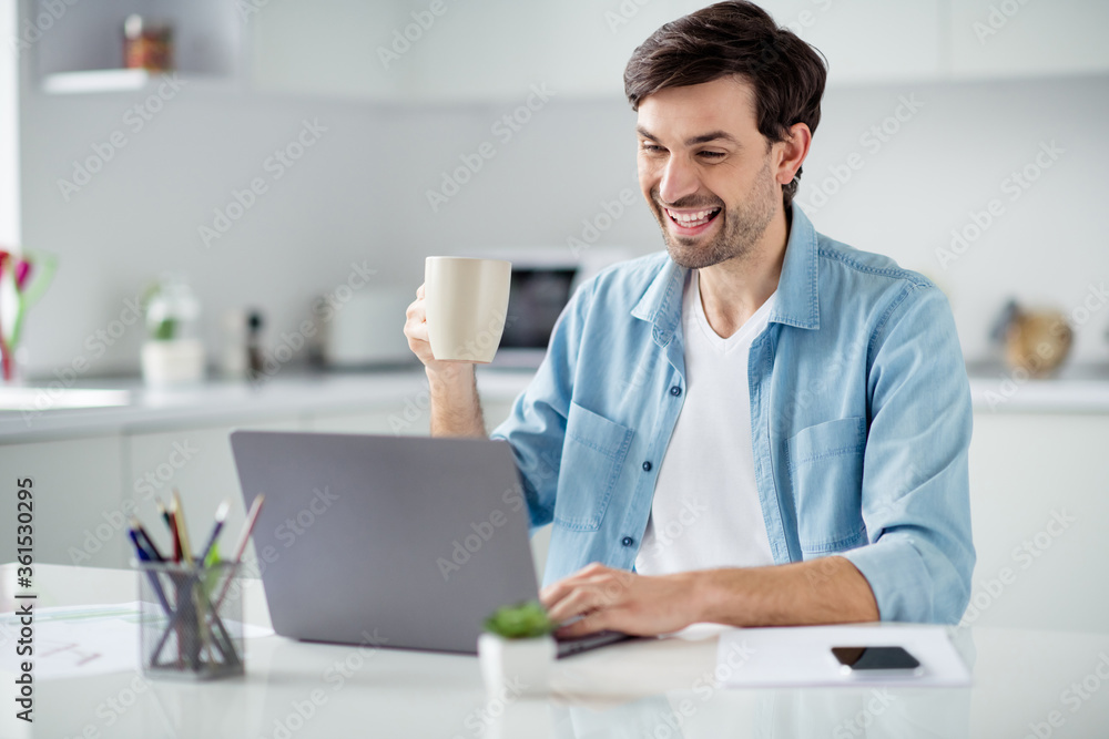 Photo of handsome guy young student browsing notebook sitting table video call teacher work house online lesson conference friendly talk drink tea good mood social distance quarantine indoors
