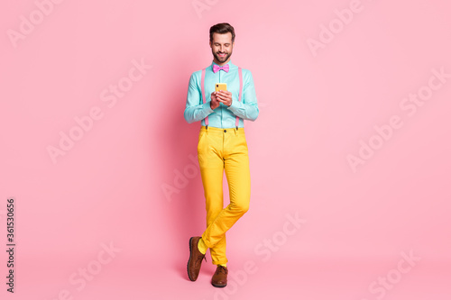 Full size photo of positive cheerful guy use cellphone enjoy repost subscribe social media news post wear shirt shoes isolated over pastel color background