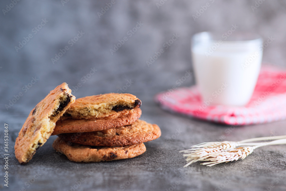 Stacked home made cookie view with a glass of milk and wheat spike studio shot Stacked home made cookie view with a glass of milk and wheat spike studio shot