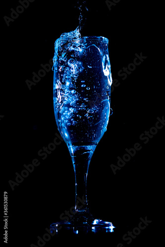 Splashes and drops of water in a glass are isolated on a black background.