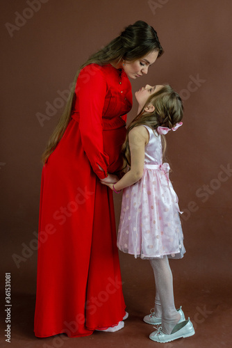 Portrait of beautiful pregnant woman and her cute daughter in studio