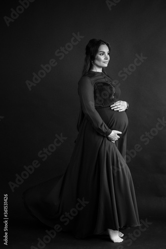 Pregnant woman in red flying dress holding her belly.