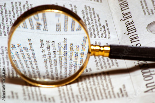 old style magnifying glass lens and newspaper. concept for fact  check  detective