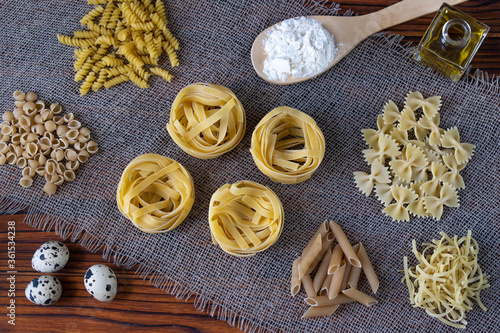 Different types of pasta on a wooden table on a tissue napkin.