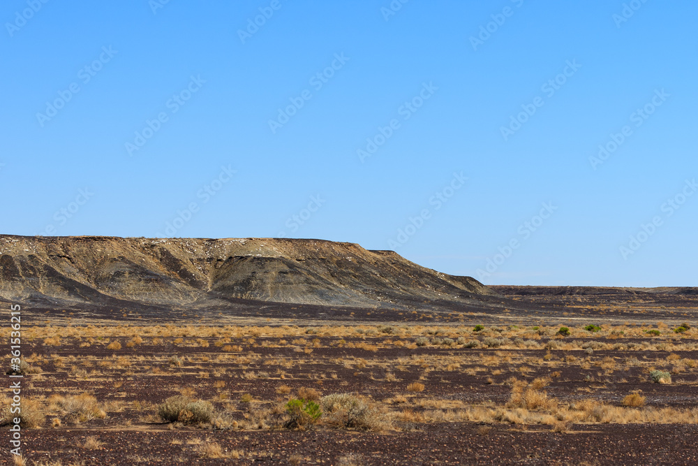 A hot, dry and bare landscape with mountains and eroded slopes in the Outback of South Australia on the way to Lake Eyre