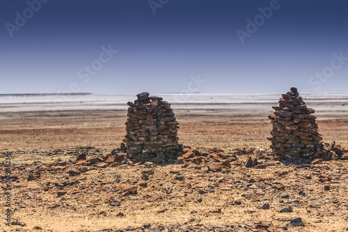 Two stone men stand in the heat on the edge of Lake Eyre at Halligan Point in the salt dry soil against background of shivering hot air over salt flats photo