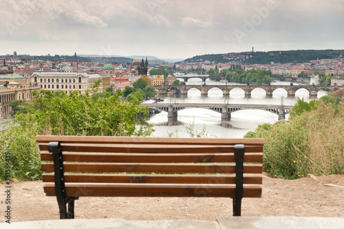 Beautiful view of the bridges of Prague over Vltava river with an empty bench ready for people in the blurred foreground