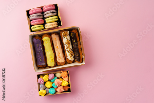 Carton boxes with eclair cakes and cookies on pink surface © fotofabrika