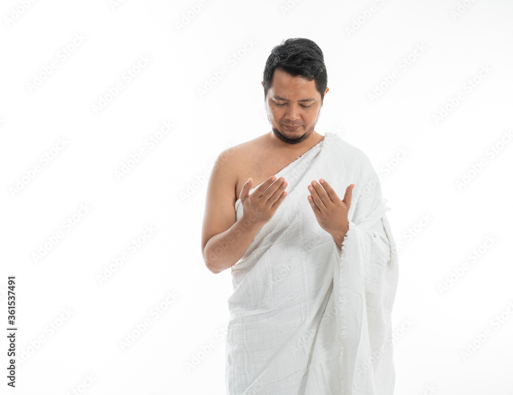 Muslim man praying while standing in white traditional clothes open his arm Muslim man praying while standing in white traditional clothes open his arm