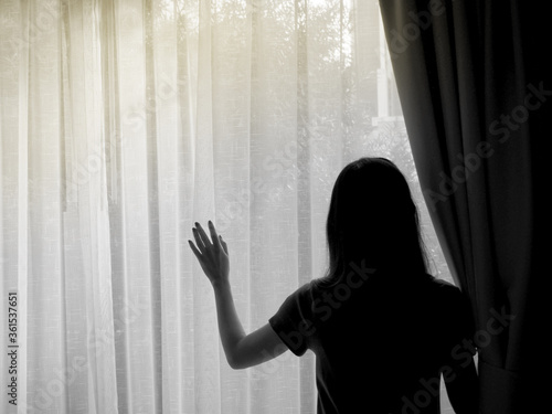 A woman standing by the window stay at home
