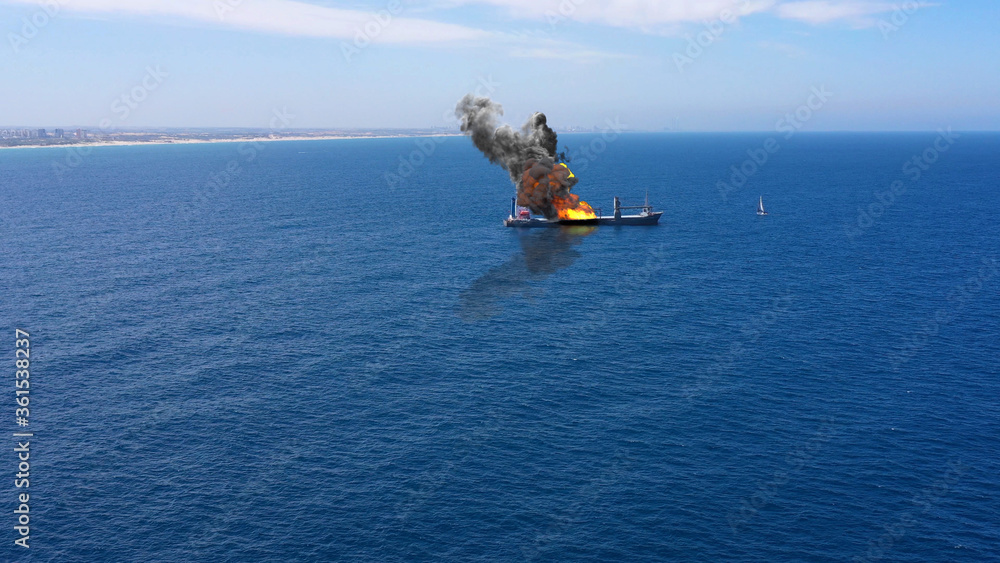 Cargo ship burning on fire with large scale smokeAerial Aerial