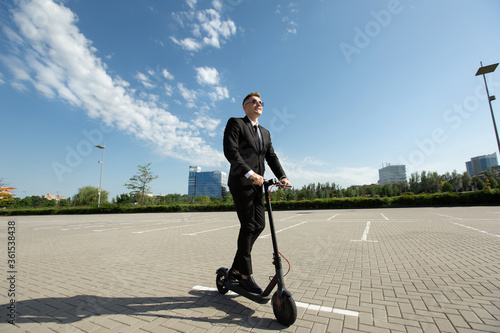 Young businessman in sunglasses on an electric scooter in the city