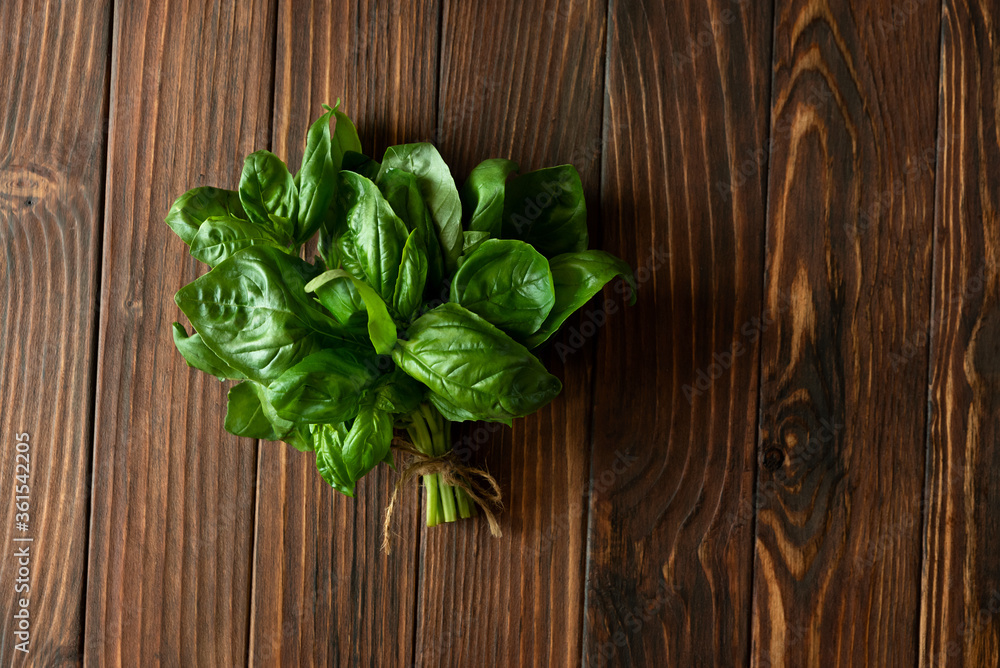 Fototapeta premium Fresh green basil on brown rustic wooden background. Top view. Flat lay