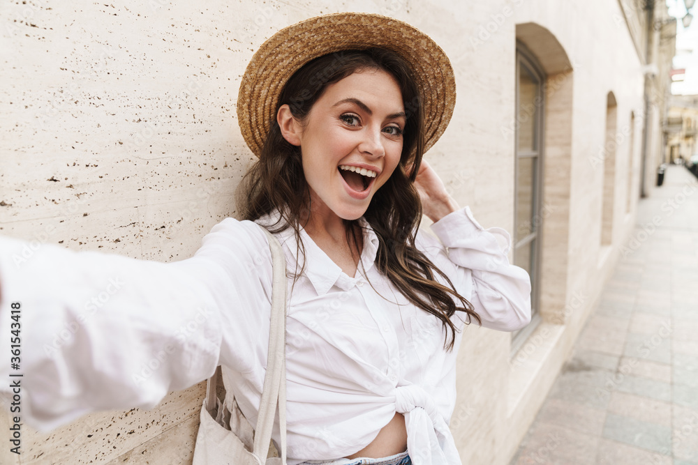 Portrait of beautiful cheerful woman smiling and taking selfie photo